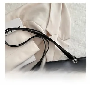 Close-up of black leather handbag featuring slim straps and metallic ring buckles