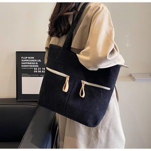 Close-up of black corduroy tote bag with double zipper pockets and wide shoulder strap