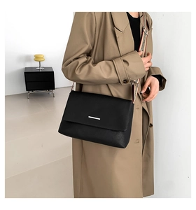 Détail du sac bandoulière en cuir grainé noir avec large bandoulière rayée colorée