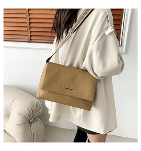 Détail du sac bandoulière en cuir grainé jaune avec bandoulière tissée à rayures
