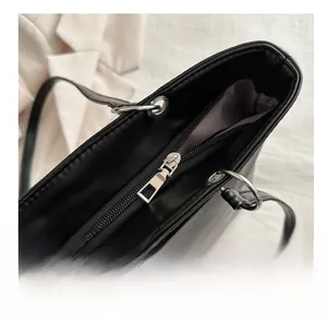 Detailed macro view of the smooth silver metal zipper and grey fabric lining on a black tote