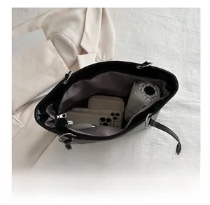 Spacious interior of black leather tote bag holding a wallet, phones, and umbrella