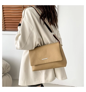 Détail du sac à bandoulière en cuir beige avec une large sangle en tissu coloré chic