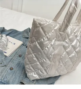Detail of silver quilted tote bag with metallic gloss texture on blue denim jacket
