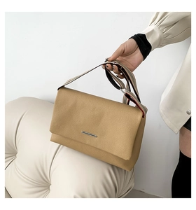 Détail du sac à bandoulière en cuir marron clair avec une sangle rayée élégante