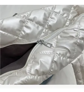 Detail of a smooth silver metal zipper on a white quilted glossy nylon handbag