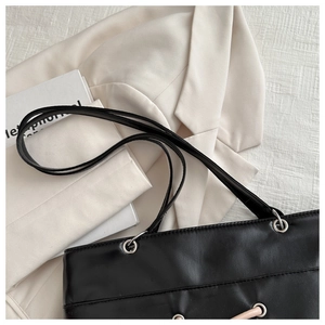 Detail of black faux leather texture with metal eyelets and beige decorative strap