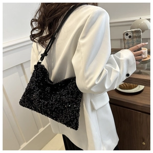 Detalle de bolso de hombro con lentejuelas negras y asa con nudo en una modelo con traje