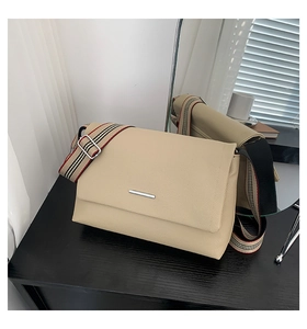 Vue détaillée du sac bandoulière beige minimaliste avec cuir texturé et sangle rayée