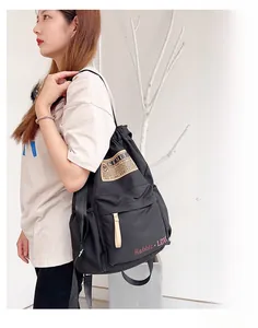 Vue détaillée du sac à dos en toile noire avec patch vintage et poche latérale