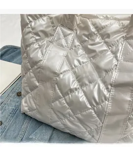Close-up of shiny quilted rhombic fabric on minimalist white shoulder bag with soft texture