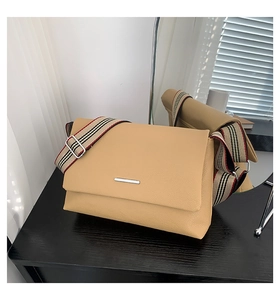 Détail du sac messager en cuir kaki avec sa large bandoulière en tissu à rayures
