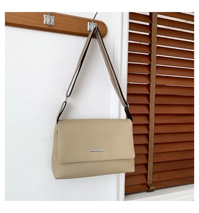 Détail du sac bandoulière beige en cuir avec sangle rayée et accessoires argentés