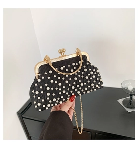 Détail d'un sac de soirée plissé noir avec perles blanches et chaîne dorée