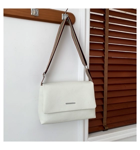 Vue détaillée du sac à bandoulière blanc texturé litchi avec barre en métal argenté