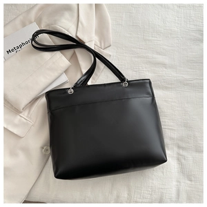 Detail of minimalist black leather tote bag with silver metal rings and chic texture