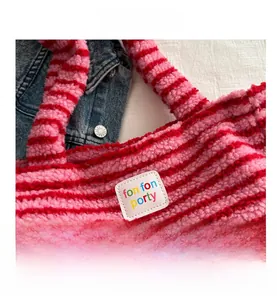 Detail van de roze en rood gestreepte pluche draagtas met logo-patch op denim