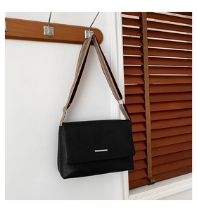 Détail du sac bandoulière en cuir noir avec bandoulière tissée à rayures colorées