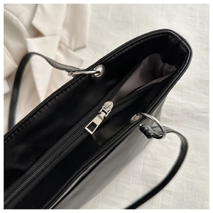 Detail of silver zipper closure and smooth black PU leather on the minimalist tote bag