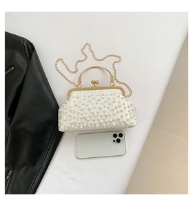 Détail d'une pochette de soirée en satin perlé blanc avec poignée dorée et mobile