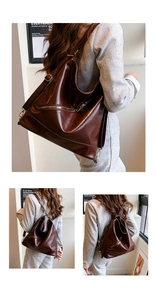 Detalle de bolso tote grande de cuero marrón oscuro con cremalleras sobre traje gris