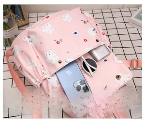 Poche avant du sac à dos rose à cordon montrant le rangement du téléphone et lunettes