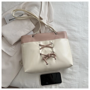 Detail of minimalist cream-pink tote bag with bow decoration and cross straps on texture background
