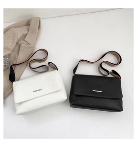 Détail de sacs en cuir à motif lychee avec bandoulières larges en tissu rayé