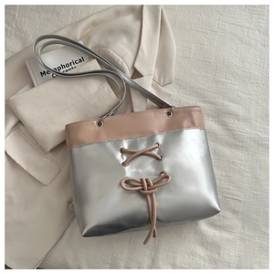 Detail of silver metallic tote with nude pink leather straps and a delicate bow tie