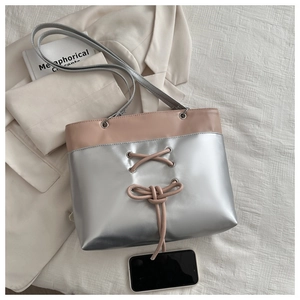 Detail of two-tone pink and silver tote bag with drawstring lace-up design and long strap