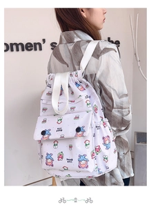 Détail du sac à dos à cordon blanc avec motifs cartoon colorés et poche à rabat