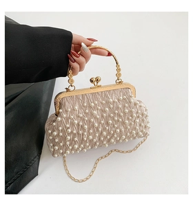 Détail du sac de soirée champagne avec poignée dorée et ornements en perles