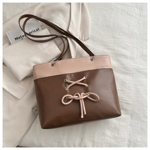 Detail of minimalist tote bag with two-tone design, crisscross drawstring and metal eyelets