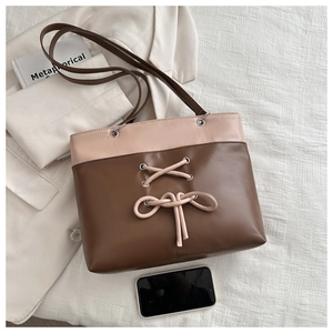 Flat lay of a beige and brown tote bag with decorative bow and long shoulder straps
