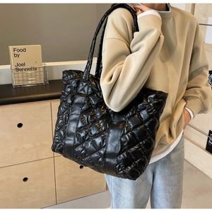 Close-up of black quilted puffer tote bag with large diamond stitching and long straps