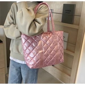 Pink metallic quilted tote bag shown on model with chic glossy finish and padded handles