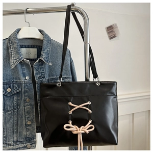 Detail of black faux leather tote bag with pink lace-up ribbon and silver metal eyelets