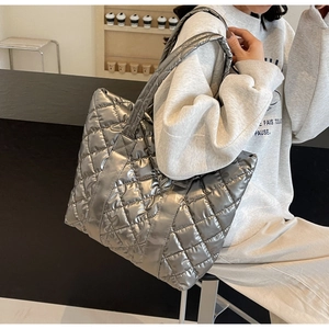 Detail of a large silver quilted tote bag made of high-quality shiny down fabric