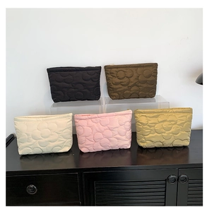 Detailed view of quilted flower pattern makeup bags in five colors with zipper closure