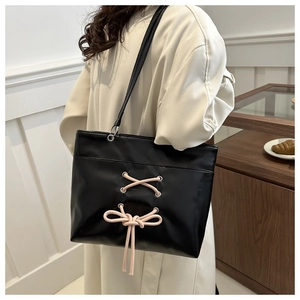 Detail of black leather tote bag with stylish pink cross lacing and bow ribbon accent