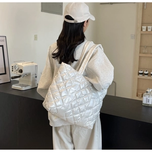 Glossy quilted shoulder bag with white rhombus pattern worn in a minimalist cafe setting