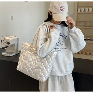 Detail view of the glossy white quilted tote bag featuring a diamond stitched nylon texture