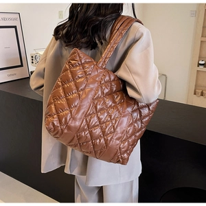 Macro shot of large dark brown quilted tote bag with glossy finish and rhombus pattern