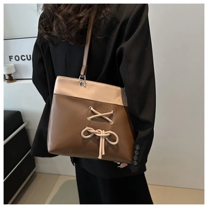 Close-up of a two-tone leather tote bag with stylish bow and lace-up details