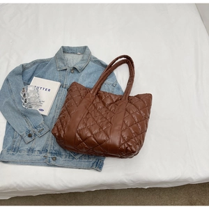 Detailed top view of a brown quilted tote bag with diamond stitching and fashion props