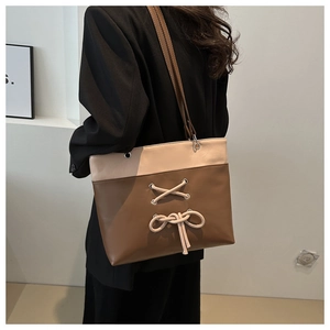 Close-up of two-tone tote bag featuring cross-laced bow detail and premium PU leather finish