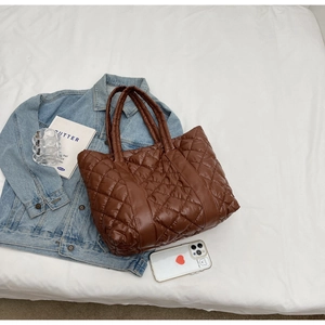 Close-up of dark brown quilted puffer tote bag with glossy nylon diamond stitching detail
