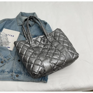 Close-up of silver quilted tote bag with metallic sheen and soft padded handles