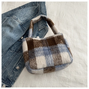 Detail der blau-braun karierten Plüschtasche mit weicher Textur auf Denimstoff