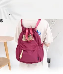 Détail du sac à dos en nylon bordeaux imperméable avec cordon et poche zippée avant